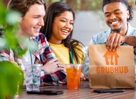 Smiling students holding a Grubhub delivery bag